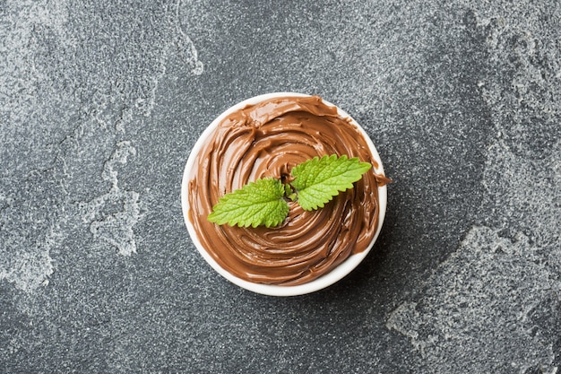 Фото Шоколадный орех нуги в тарелку на темном фоне бетона с лесными орехами.