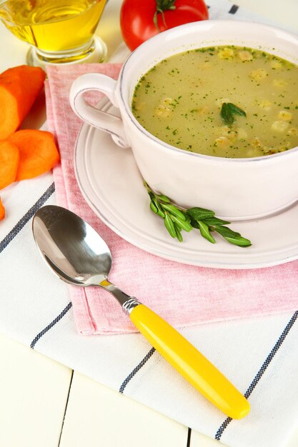 Nourishing soup in pink pan on wooden table closeup