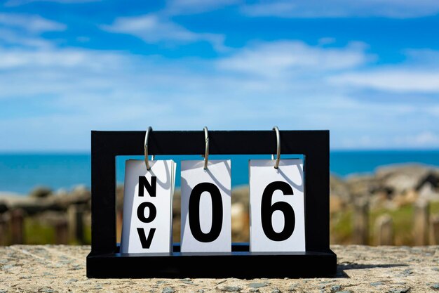 Photo nov 06 calendar date text on wooden frame with blurred background of ocean