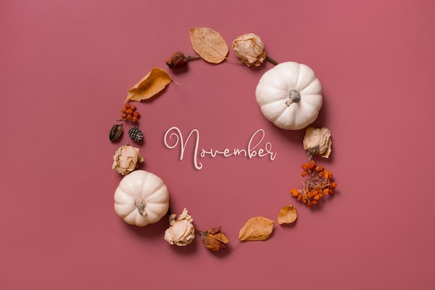 November-inscriptie in krans van pompoenbladeren en bloemen met bovenaanzicht van bessen