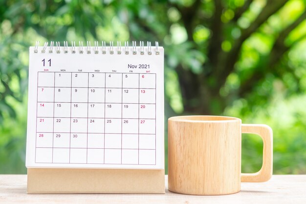 November month, calendar desk 2021 for organizer to planning
and reminder on wooden table with green nature background.