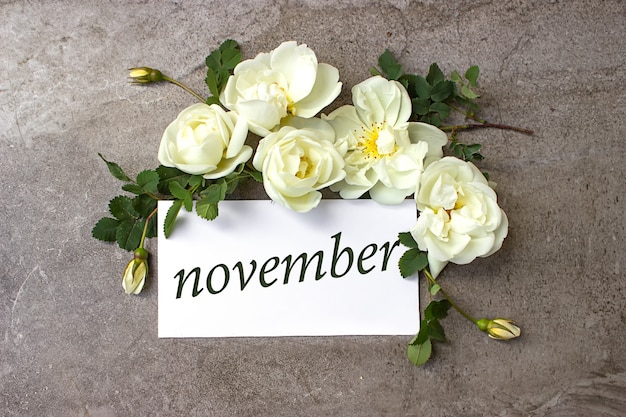 Novembre. mese, mese di calendario. bordo di rose bianche su sfondo grigio pastello con data di calendario. autunno, concetto di mese dell'anno.