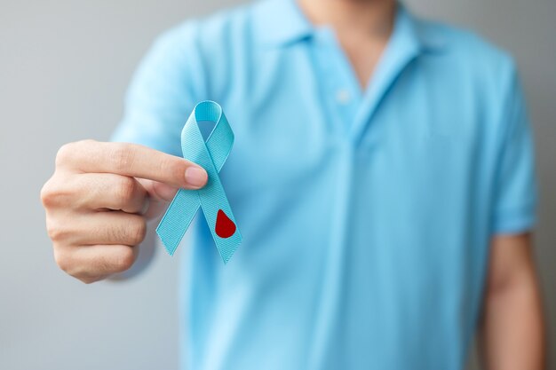 Ноябрь Всемирный день борьбы с диабетом Месяц осведомленности, мужчина держит голубую ленту с формой капли крови для поддержки жизни людей, профилактики и болезней. Здравоохранение, концепция дня рака простаты
