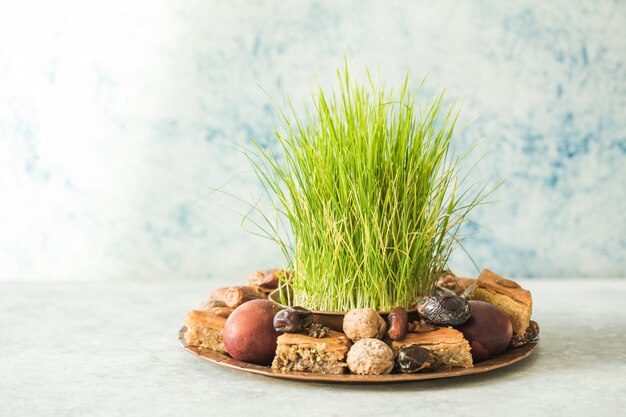 Novruz traditioneel dienblad met groen tarwegras semeni of sabzi, snoep en droog fruit pakhlava op witte achtergrond. Lente-equinox, Azerbeidzjan kopie ruimte