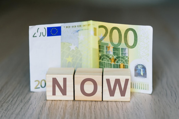 Now word on wooden cubes blocks, money 200 Euro banknotes. Management big salary career concept.