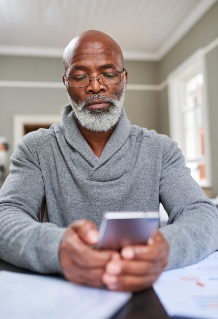 Now you can bank from anywhere Cropped shot of a senior man using his cellphone while working on his finances at home