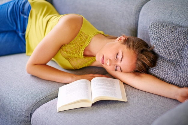 Nowhere more relaxing than home Shot of a young woman sleeping beside a book on her sofa at home