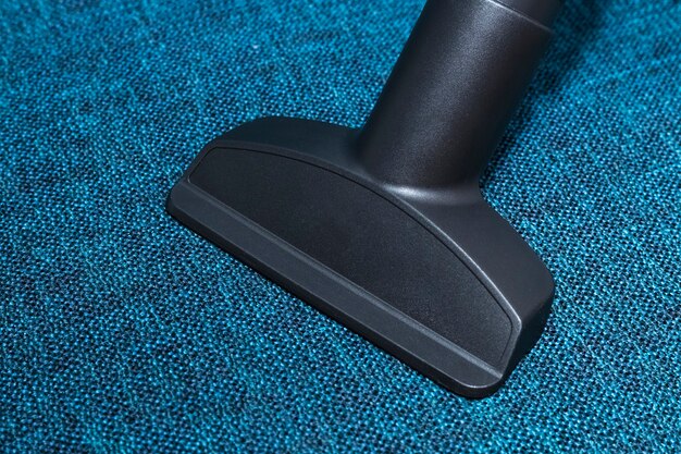 Nozzle for a vacuum cleaner against a blue fabric of upholstered furniture