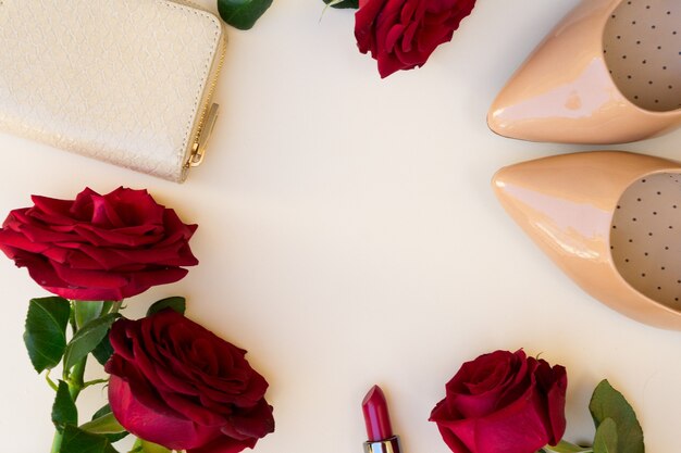 Nude colored high heels with lipstick, fresh red roses and wallet hero header