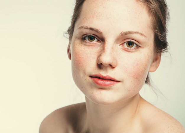 Nude shoulders beautiful freckles woman face portrait young. Blue background.