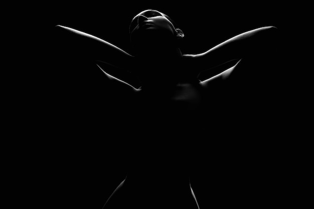 Nude Woman silhouette under light in the dark studio