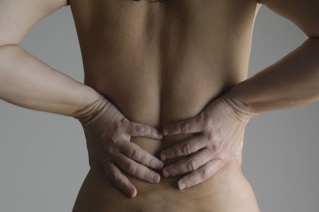 Nude woman with a back pain