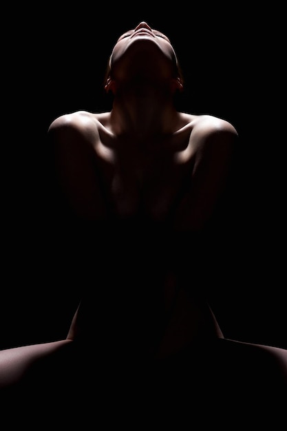 Siluetta nuda della giovane donna nell'oscurità