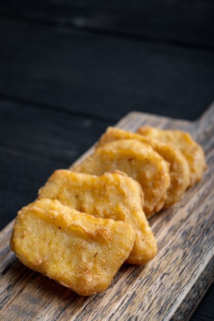 Nuggets gepaneerd op zwarte houten tafel.