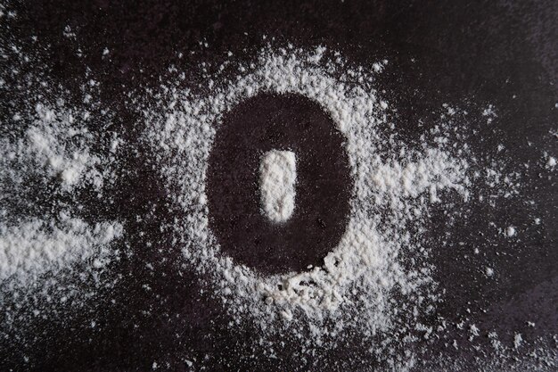 The number 0 is written on scattered white flour through a stencil