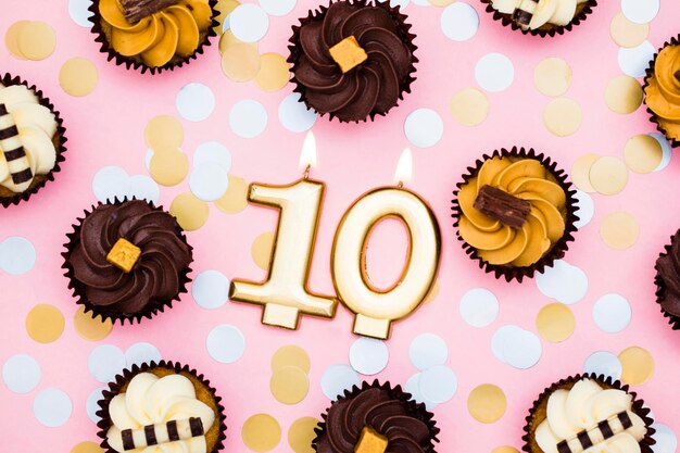 Photo number 10 gold candle with cupcakes against a pastel pink background