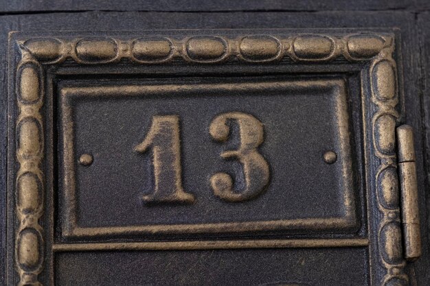 Number 13 on metal door Old vintage retro copper plate with the number thirteen