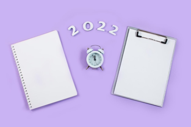 Number 2022 and Paper blank notepad with alarm on purple background Business education working concept