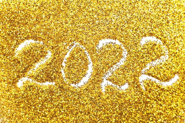 Photo the number 2022 written on golden confetti christmas or new year background