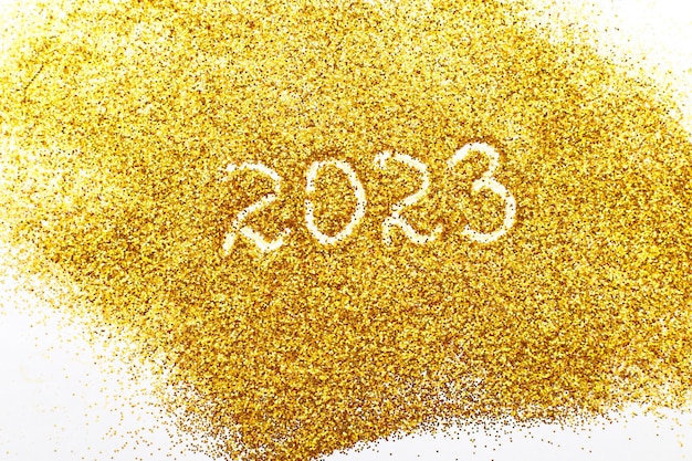 Number 2023 written on golden confetti christmas or new year background