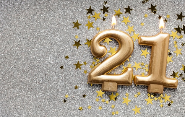 Number 21 gold celebration candle on star and glitter background