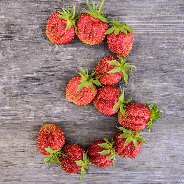 Number 3 of strawberries on wooden background