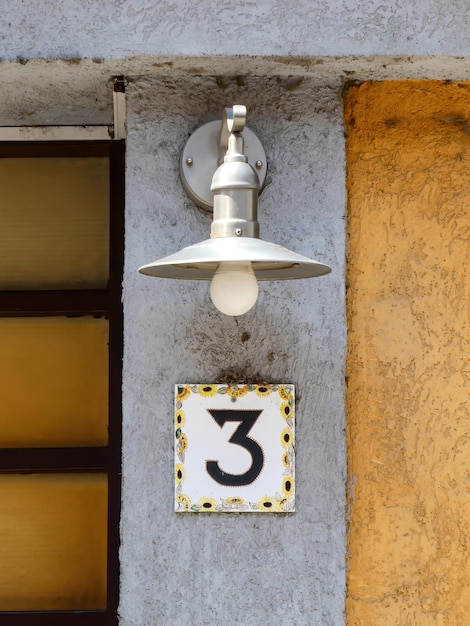 Il numero 3 sul muro davanti alla casa con sopra una lampada