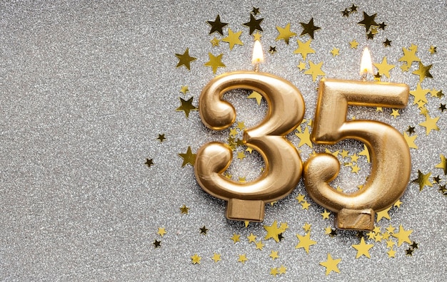 Number 35 gold celebration candle on star and glitter background