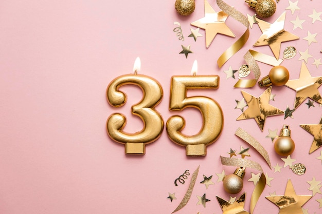 Number 35 gold celebration candle on star and glitter background