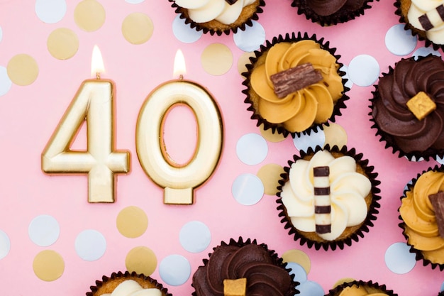 Photo number 40 gold candle with cupcakes against a pastel pink background