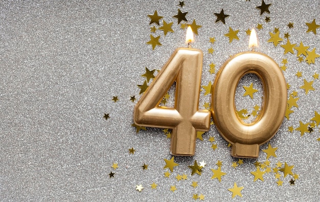 Number 40 gold celebration candle on star and glitter background