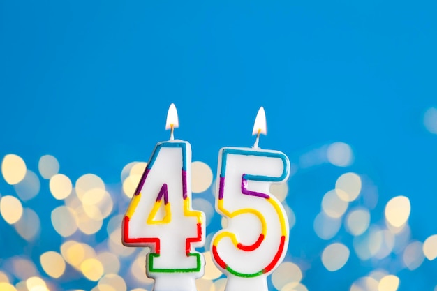 Number 45 birthday celebration candle against a bright lights and blue background