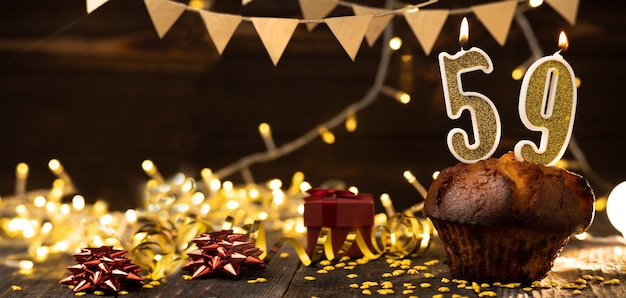 Number 59 golden festive burning candles in a cake wooden holiday background fifty nine years since the birth the concept of celebrating a birthday anniversary holiday Banner