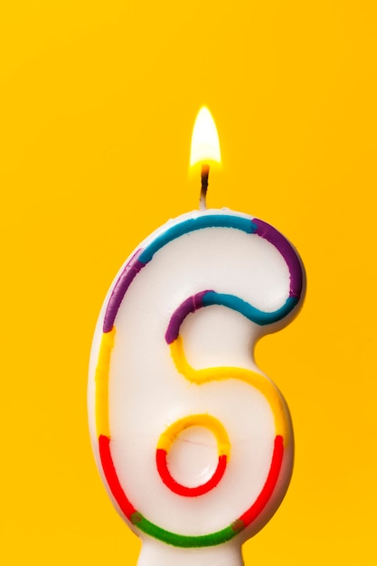 Number 6 birthday celebration candle against a bright yellow background