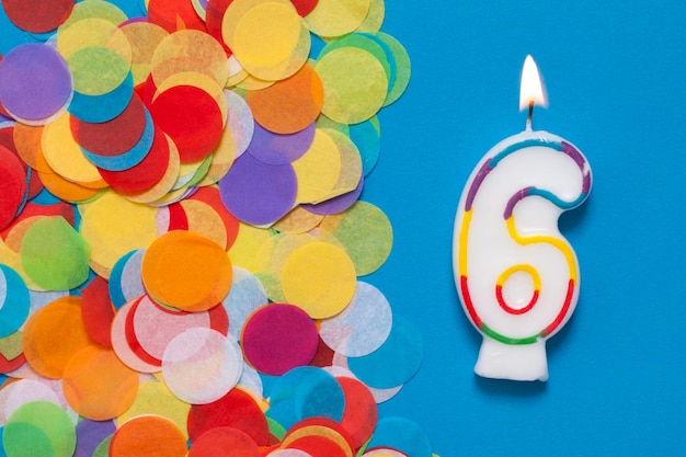 Number 6 celebration candle with party confetti