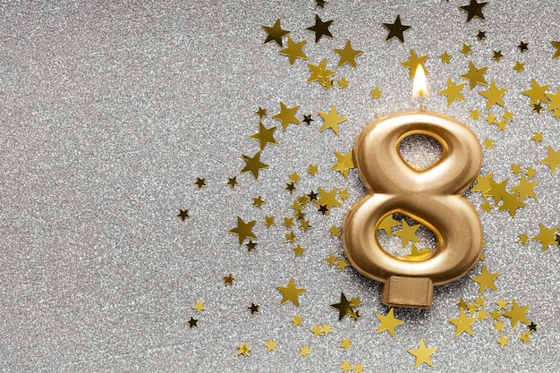 Number 8 gold celebration candle on star and glitter\
background