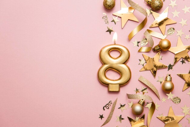 Number 8 gold celebration candle on star and glitter background