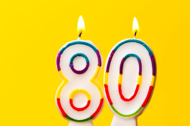 写真 明るい黄色の背景に80番の誕生日のお祝いキャンドル