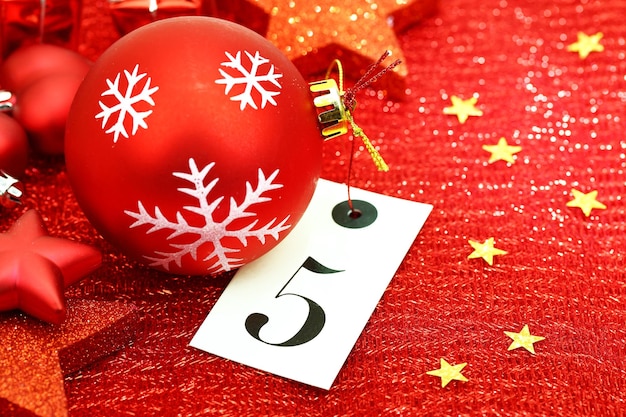 Number five on tag and Christmas ornamets on red background