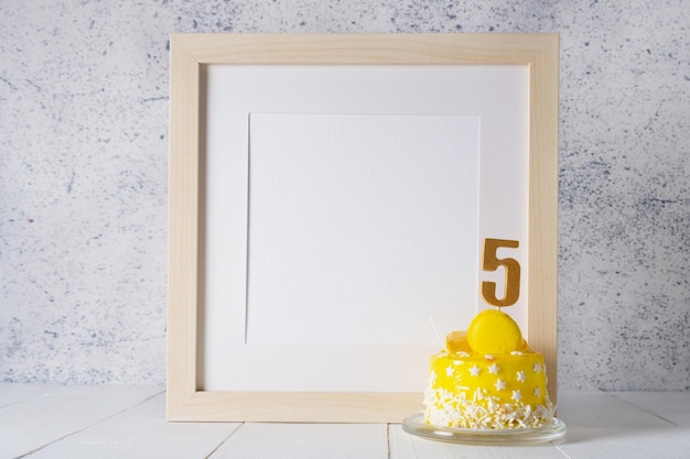 복사 공간이 있는 흰색 프레임 모형 옆에 있는 노란색 케이크의 숫자 5