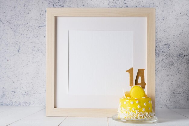 The number Fourteen on the yellow cake next to the white frame mockup with copy space