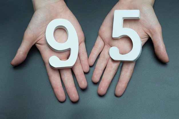 The number ninetyfive on a dark background The hands are holding the numbers