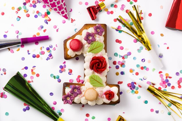 Торт номер один украшен цветами и печеньем на конфетти