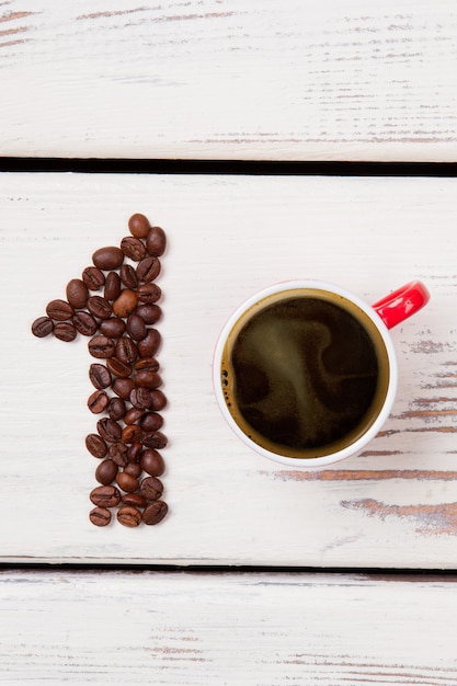 Number one made of roasted coffee beans. Cup of fresh hot coffee top view. White wooden planks surface.