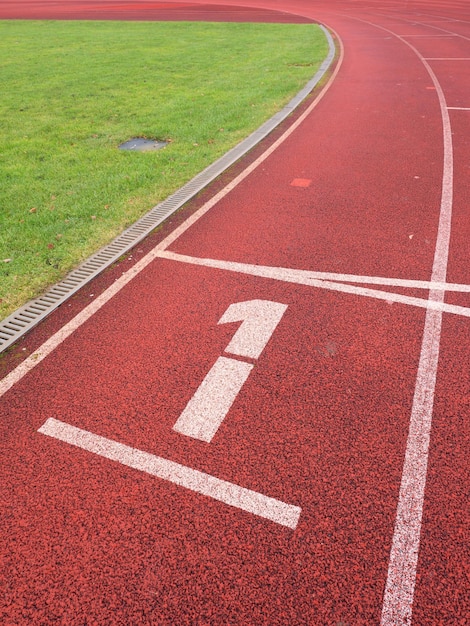 写真 スタジアムのレースコースの赤いゴムレースコースに1番の白いトラック番号