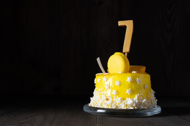 The number Seven on a yellow cake for an anniversary or birthday in a dark key