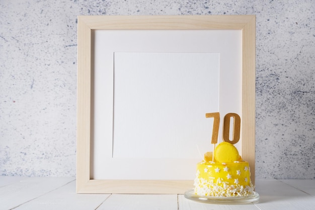 The number Seventy on the yellow cake next to the white frame mockup with copy space