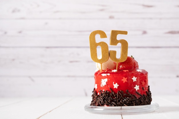 The number Sixty five on a red birthday cake on a light background