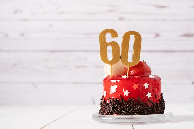 Photo the number sixty on a red birthday cake on a light background