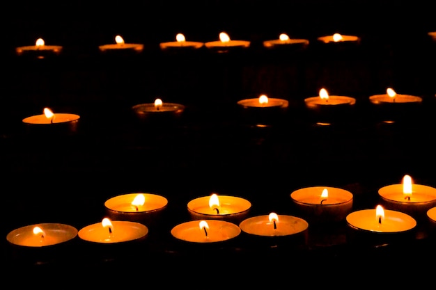 A number of small round candles in the dark church